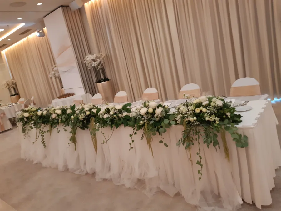 Dekoriran stol za mladence s cvijećem u sali za vjenčanje.