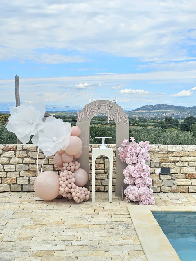 Dekoracija s balonima i cvijećem pored bazena s natpisom "From Miss to Mrs".