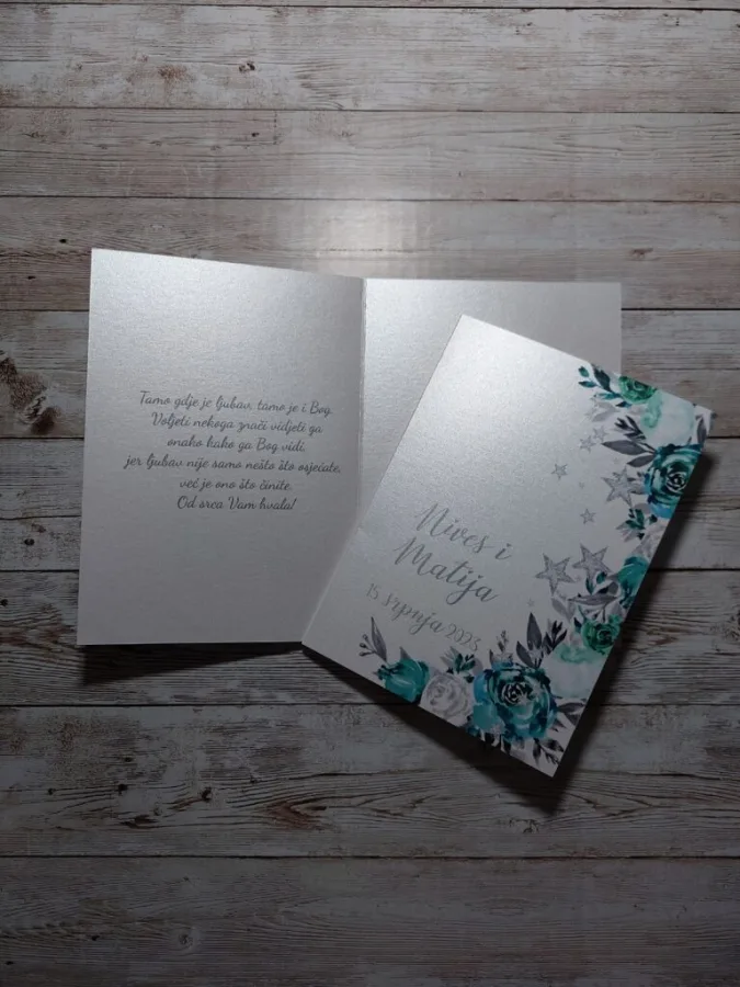 Zahvalnica za vjenčanje u obliku čestitke s mjestom za fotografiju para i citatom za goste. Na početnoj stranici je ime mladenaca i njihov datum, a dizajn je bijele i plave ruže s zvijezdicama.