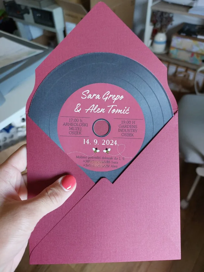 Pozivnica u obilku gramofonske ploče s imenima mladenaca u ružičastoj kuverti.