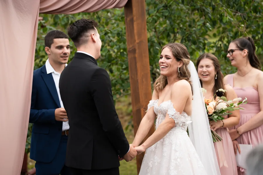 Mladenci se drže za ruku okrenuti jedno prema drugome usred obredne ceremonije.