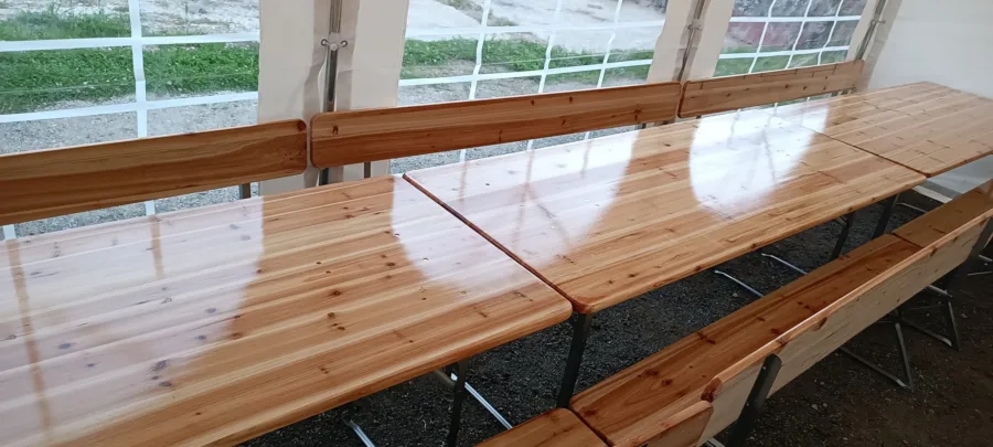 Drveni stolovi i klupe u šatoru za najam za vjenčanja.