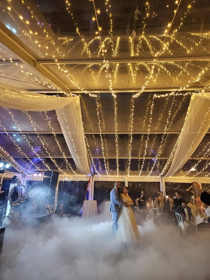 Mladenci plešu prvi ples u magli pod lampicama u Heritage Event Venue.