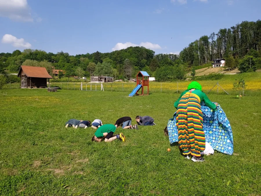 Djeca se igraju na travi s klaunom.