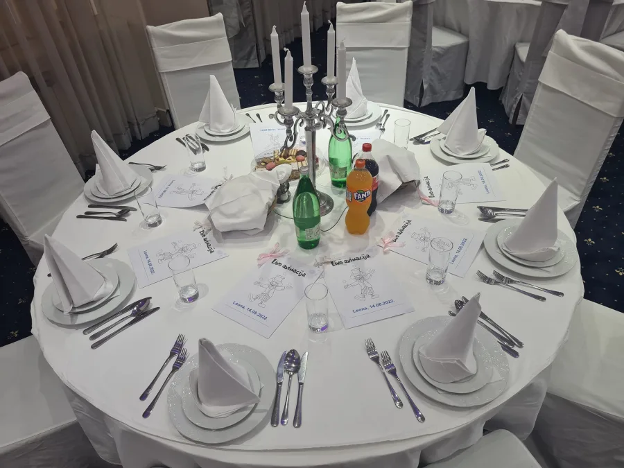 Bijeli okrugli stol i stolice u sali za vjenčanje s crtežom klauna za animaciju djece.