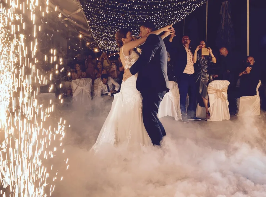 Mladenci plešu prvi ples, a oko njih gore prskalice i dimi se magla ili suhi led.