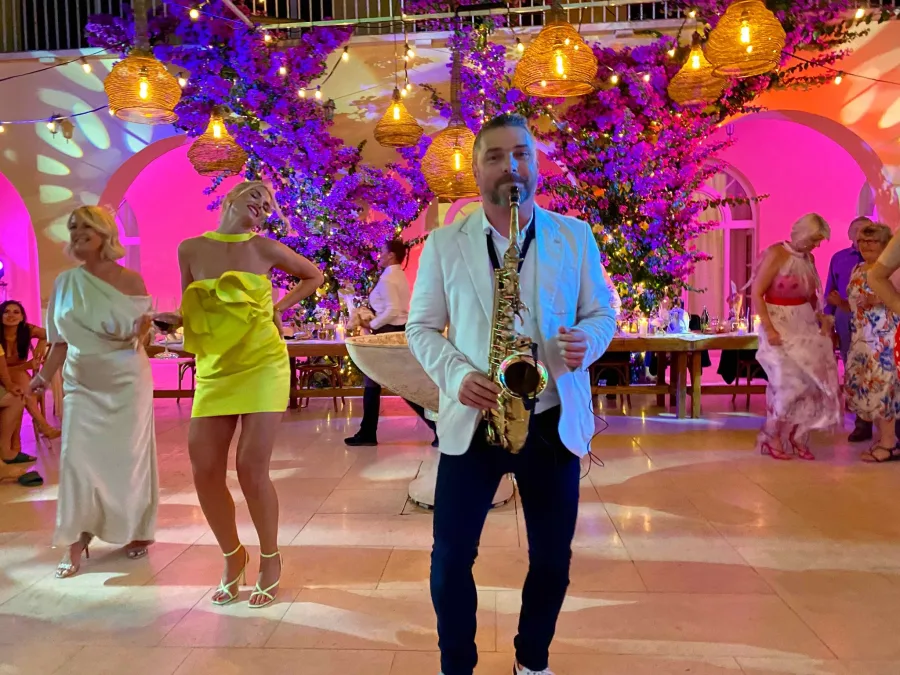 Saxofonist svira saxofon na vjenčanju dok uzvanici plešu.