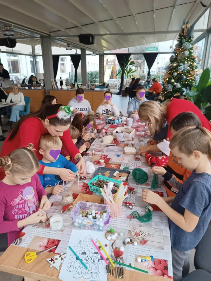 Djeca za stolom izrađuju ukrase za vrijeme Božića s animatorima.