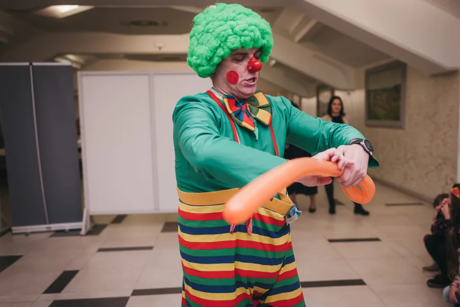 Klaun izrađuje životinju s narančastim balonom.