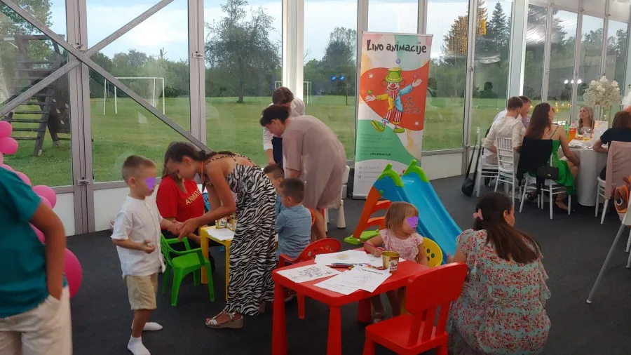 Djeca u sali za vjenčanje s animatorima se igraju.