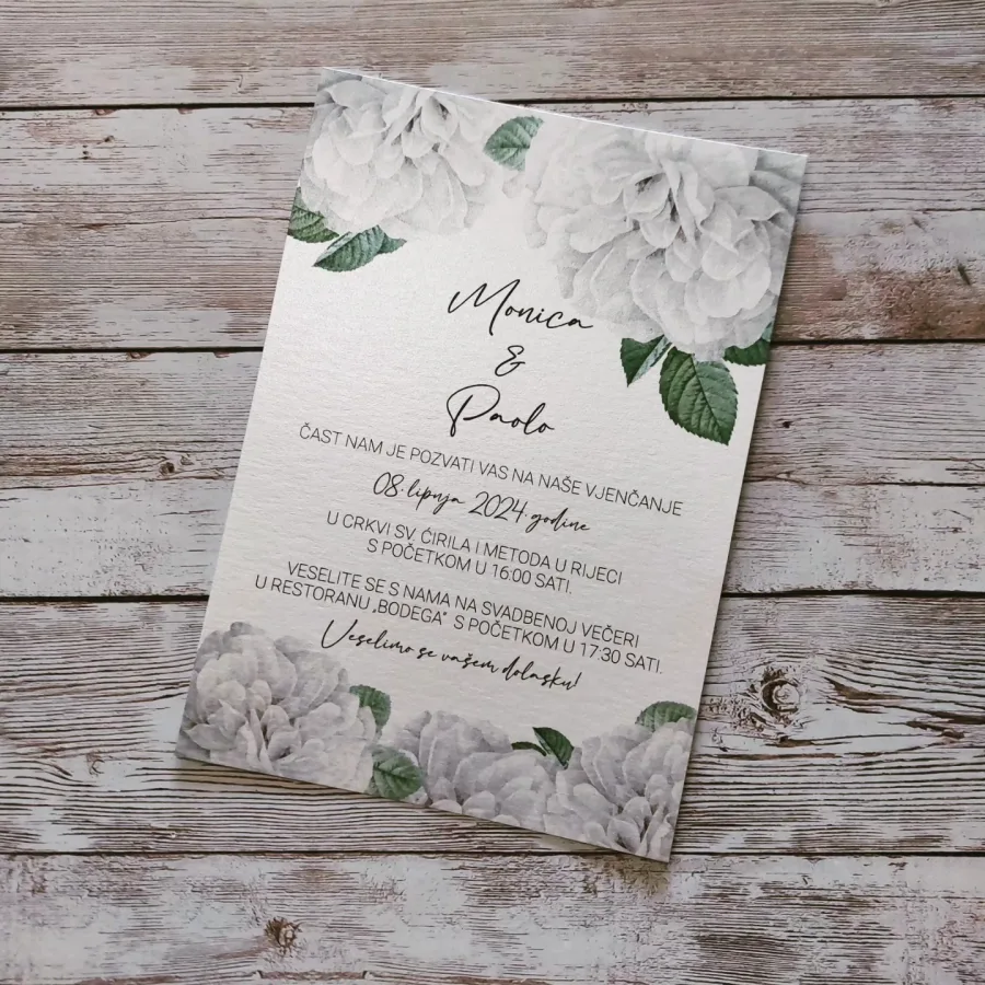 Pozivnica za vjenčanje s velikim bijelim cvijećem i zelenim listovima.