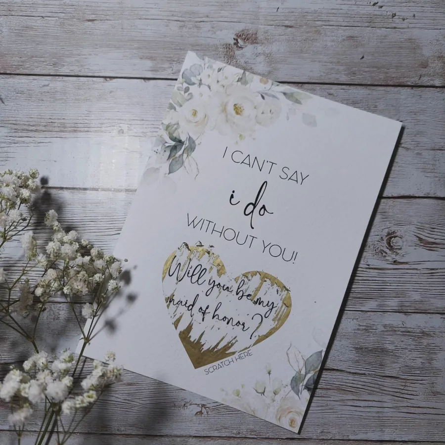 Pozivnica za kumstvo s grebalicom od zlatnog srca na bijelom papiru s bijelim ružama i zelenim lišćem.