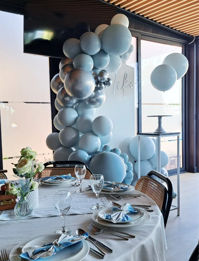 Dekoracija s plavim balonima i natpisom "Niko" za krštenje djeteta u restoranu.