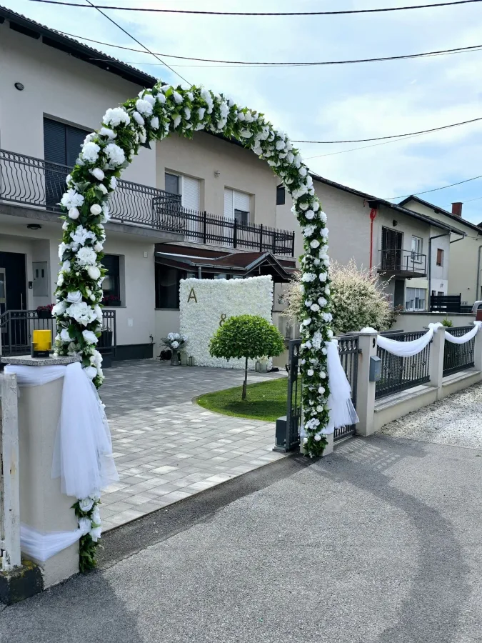 Dekoracija kuće za vjenčanje - dekoriran ulaz u dvorište te bijeli zid od cvijeća za slikanje.