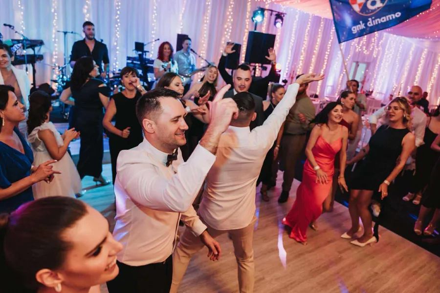 Gosti vjenčanja plešu na podiju dok Grupa Joy svira.