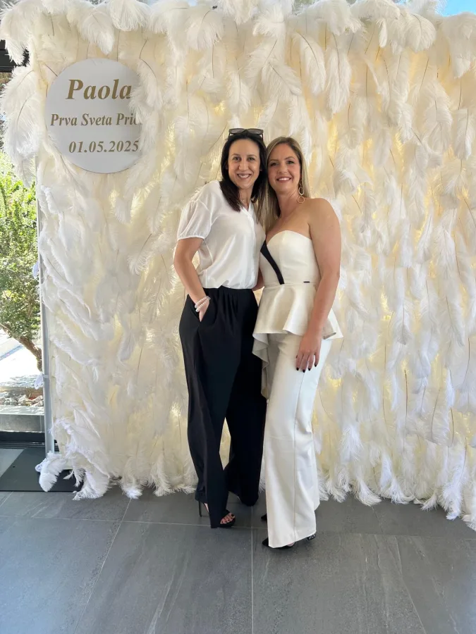 Dvije ženske osobe se slikaju u kutku za slikanje i u pozadini bijeli zid od perja.