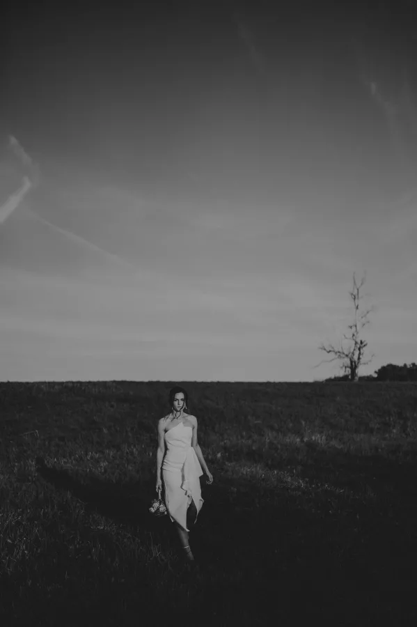 Mladenka u vjenčanici korača kroz nisku travu.