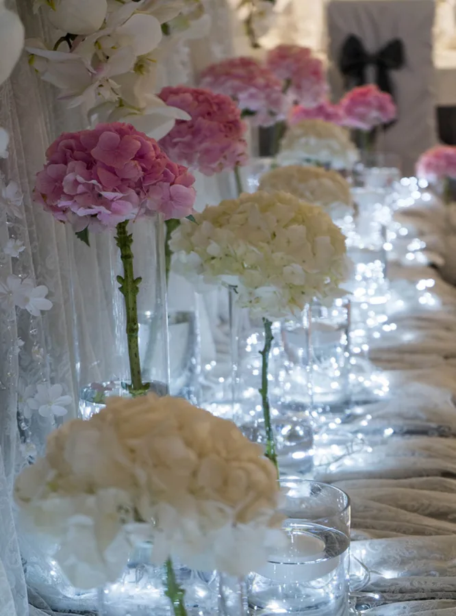 Plave lampice i cvijeće u podnožju stola za mladence.