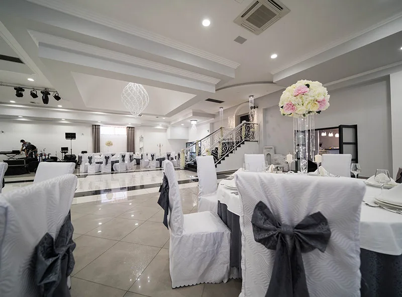 Bijele navlake za stolice sa svezanim mašnama u sali za vjenčanje.