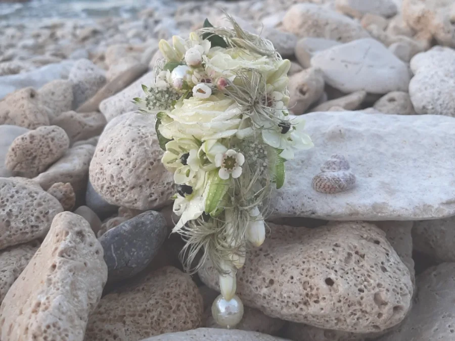 Cvjetna dekoracija s biserom na kamenoj plaži.