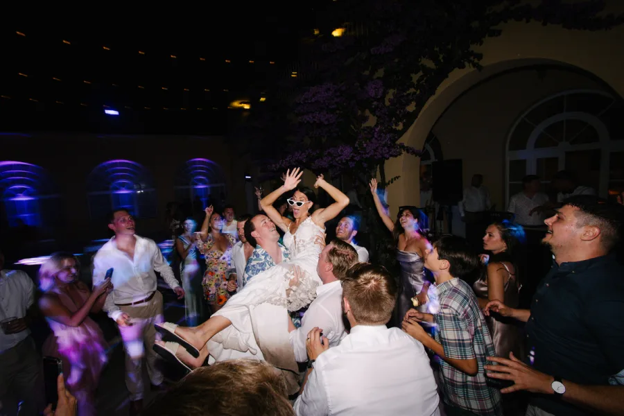 Gosti vjenčanja dižu mladu u zrak na plesnom podiju.