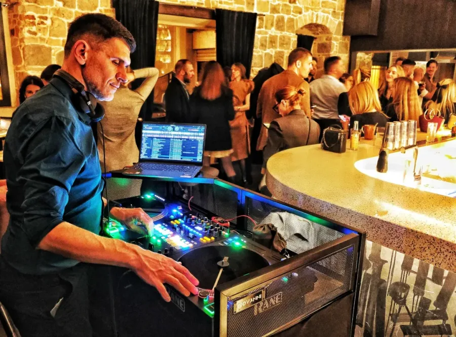 Dj na vjenčanju za misketom dok gosti plešu.