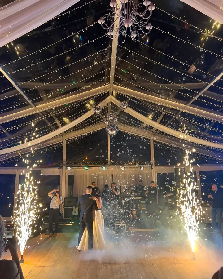 Mladenci plešu prvi ples s prskalicama i balnočićima u šatoru za vjenčanje.