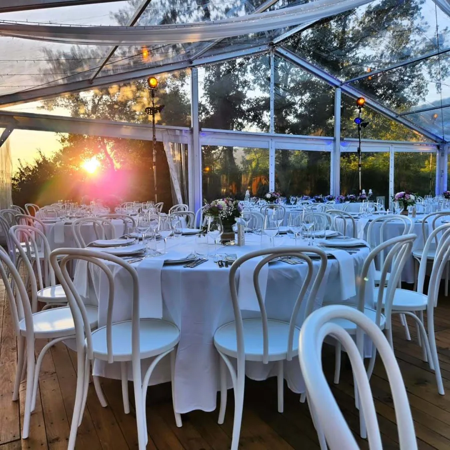 Okrugli bijeli stol u šatoru za vjenčanje na zalasku sunca.