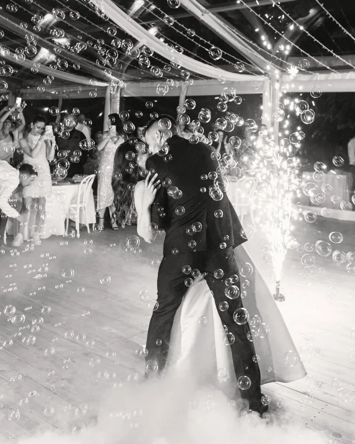 Mladenci koji se ljube na prvom plesu s baloničićima i maglom.