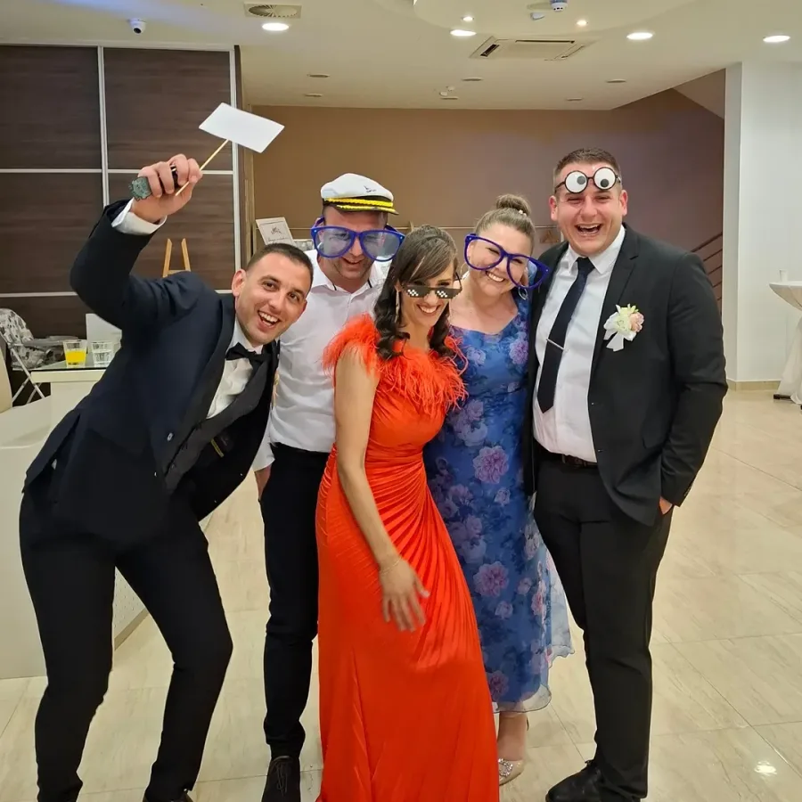 Uzvanici vjenčanja se slikaju skupa ispred photobootha.