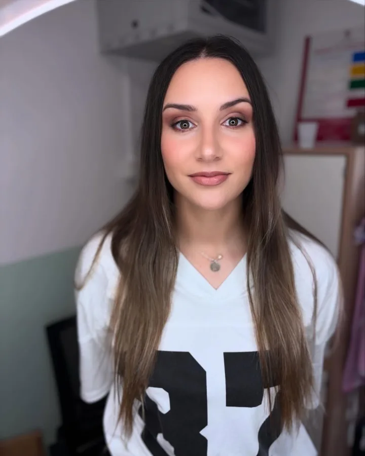 Žena duge smeđe kose decentno našminkana.