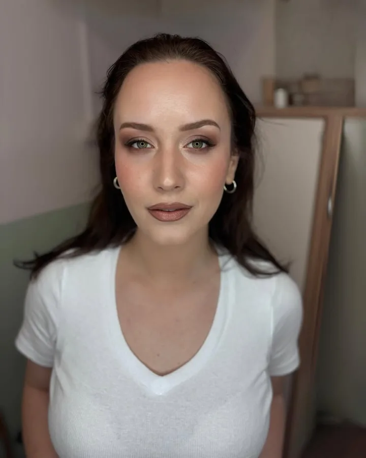 Žena smeđe kose našminkana u smeđim tonovima s istaknutim očima.