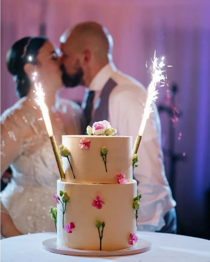 Trotaz za vjenčanje s prskalicama i mladenci koji se ljube u pozadini.