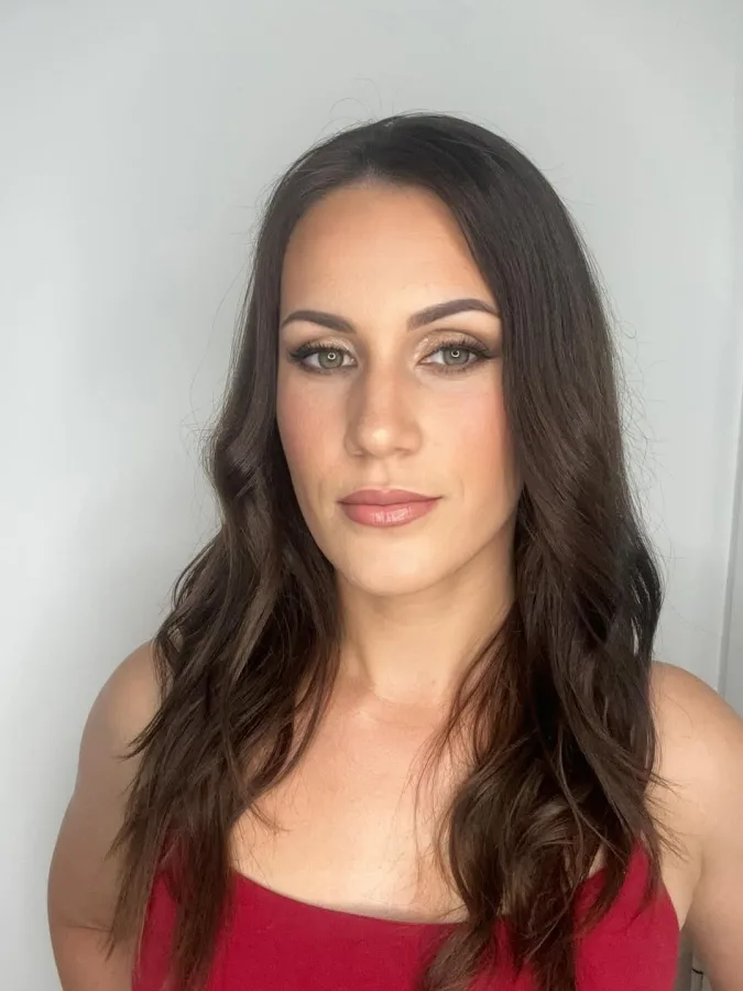 Žena valovite smeđe kose s decentnom šminkom.