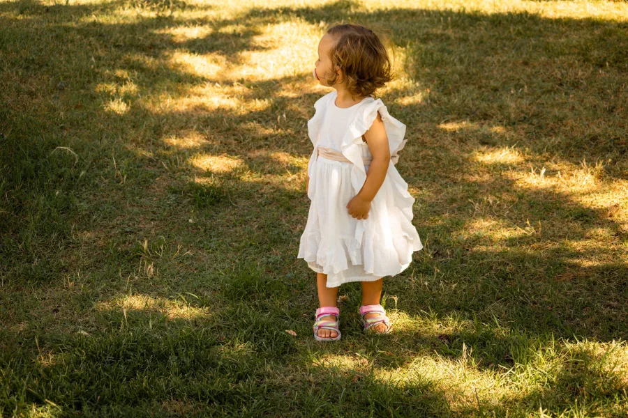 Dijete u bijeloj haljinici na travi u parku - Fotograf za vjenčanja i krštenja Split.