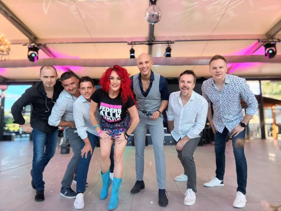 Grupa joy slika na vjenčanju s pozornicom u pozadini.