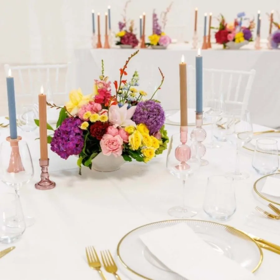 Okrugli stol za vjenčanje s šarenim buketom i svijećama.
