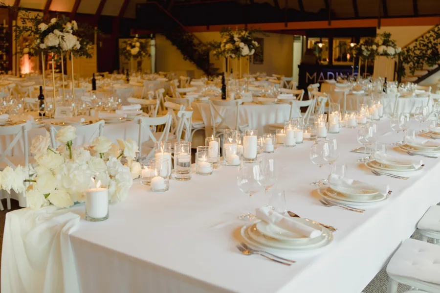 Uređena sala za vjenčanje s okruglim stolovima i bijelim stolnjacima.