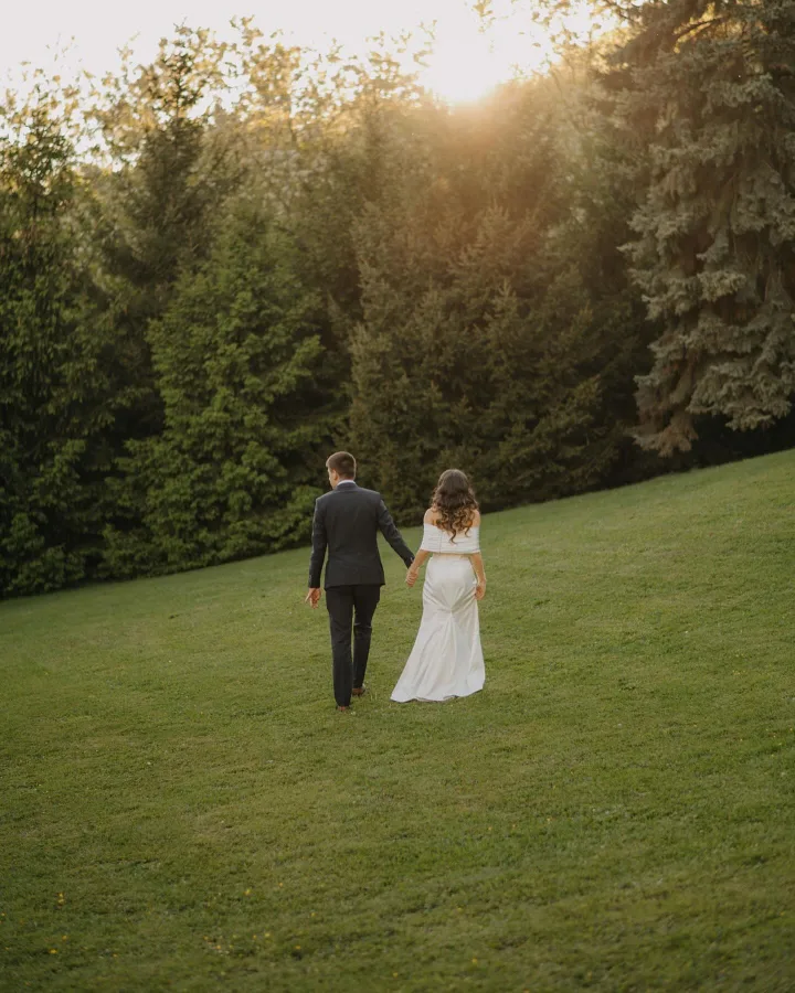 Mladenci se drže za ruku dok hodaju livadom u prirodi na imanju Marincel.