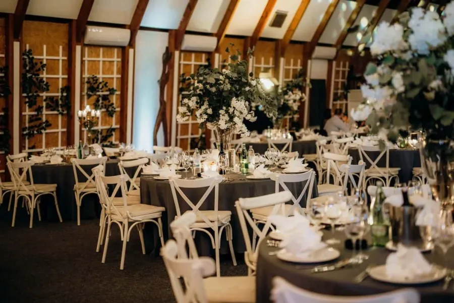 Dekorirani stolovi sa sivim stolnjacima i bijelim stolicama.