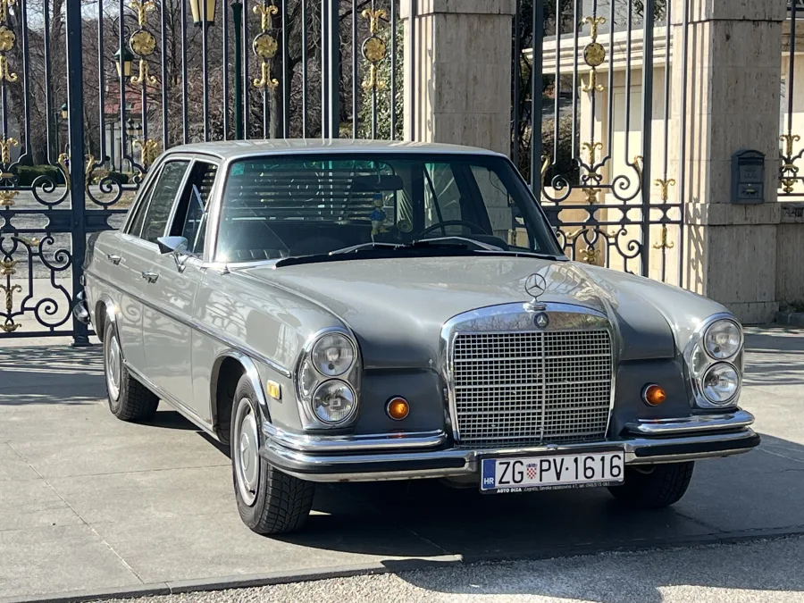 Mercedes Oldtimer 1967 parkiran ispred velikih dvorišnih vrata.