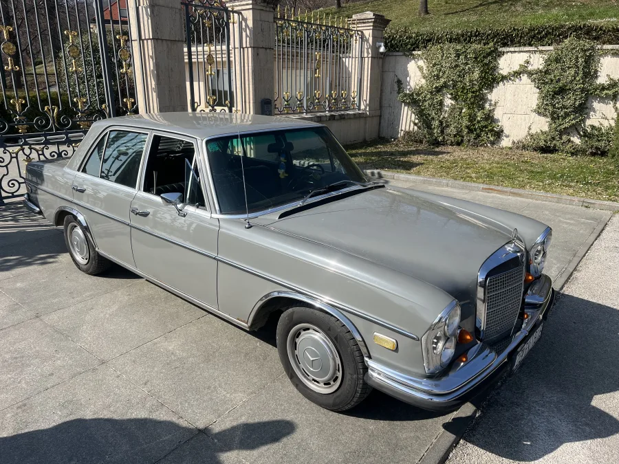 Oldtimer Mercedes sivi ispred dvorišnih vrata.