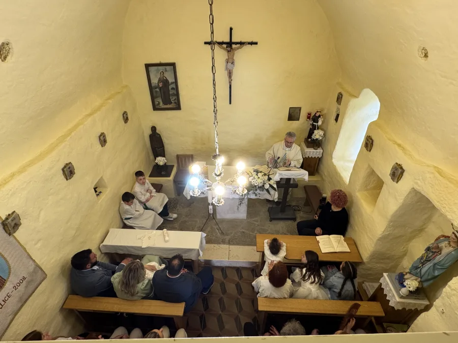 Svećenik za oltarom čita svete spise za vrijeme obreda krštenja djeteta u crkvi.