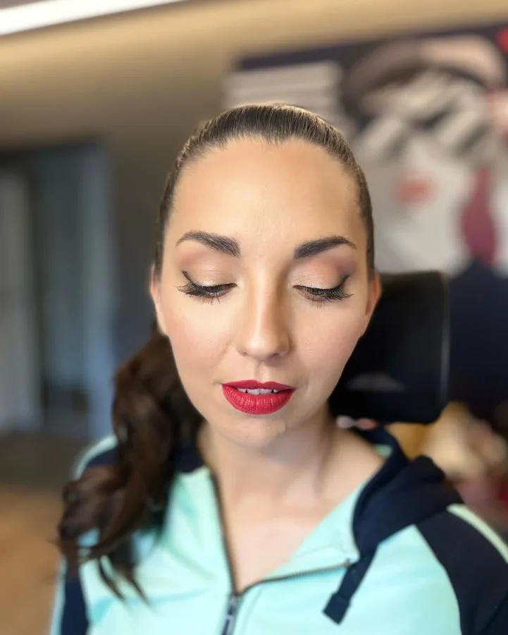 Djevojka našminkana s crvenim ružom za usne i lagano smećkastim sjenilom te crnim eyelinerom.