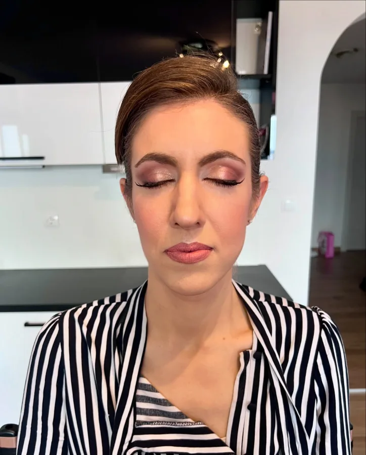 Djevojka našminkana s naglašenim očima smećkaste i bijele palete sjenila i mesnate boje ruža.