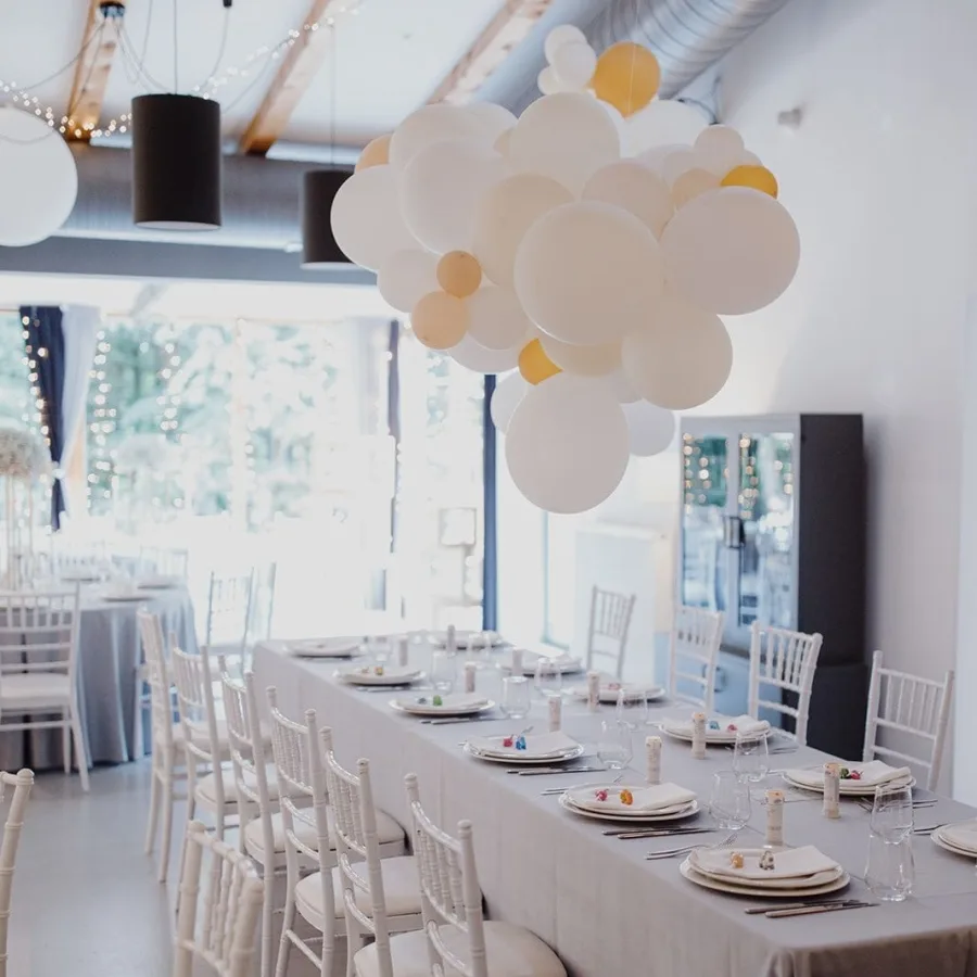 Veliki bijeli stol za proslave iznad kojeg su bijeli baloni.