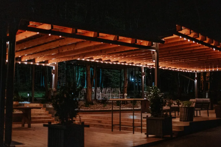Klub šumica natkrivena terasa u šumi s rasvjetom.