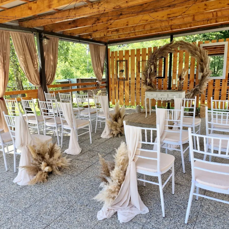 Bijele stolice pred malim stolićem za ceremoniju vjenčanja.