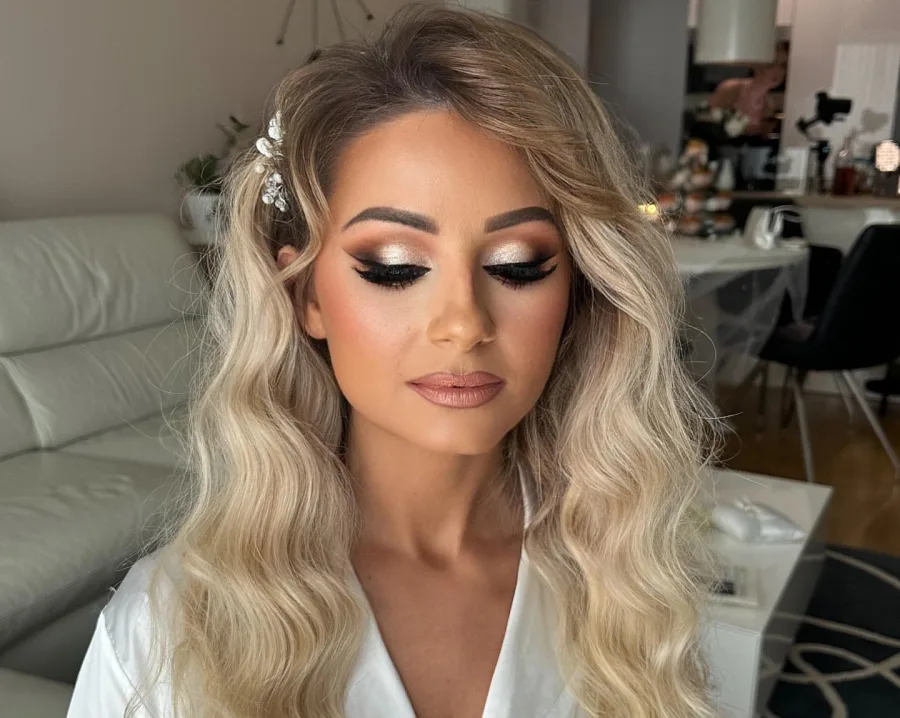 Istaknute smokey eyes oli s eyelinerom i svečana šminka na ženi valovite plave kose.