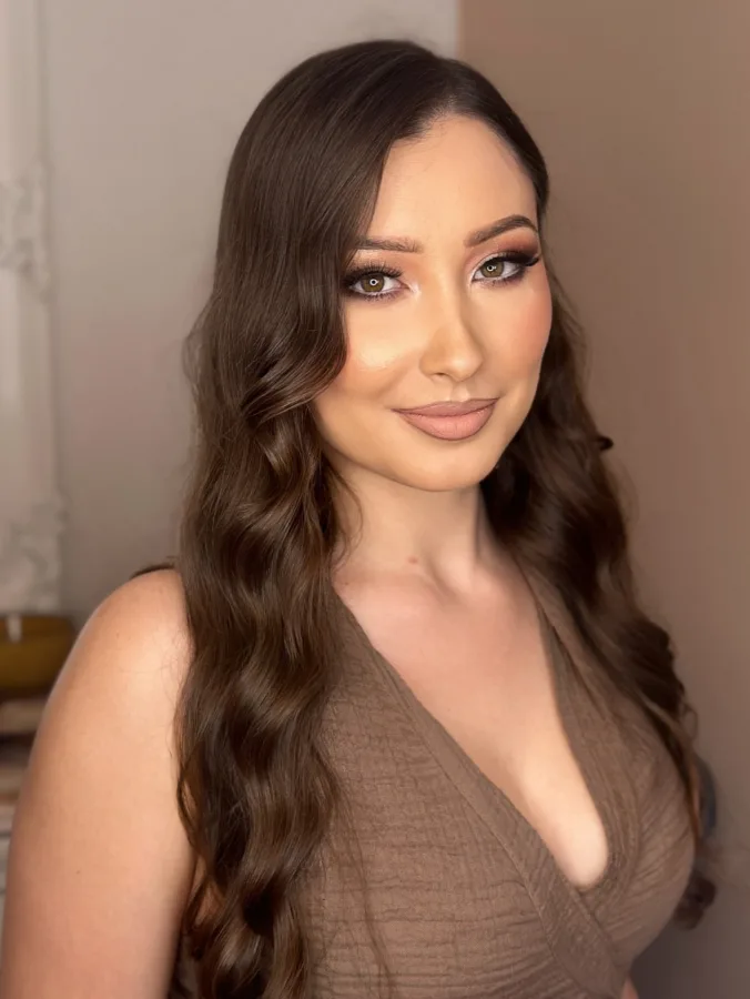 Žena valovite smeđe kose s trajnom pminkom usana, sjenilom i šminkom u prirodnim tonovima Zagreb.